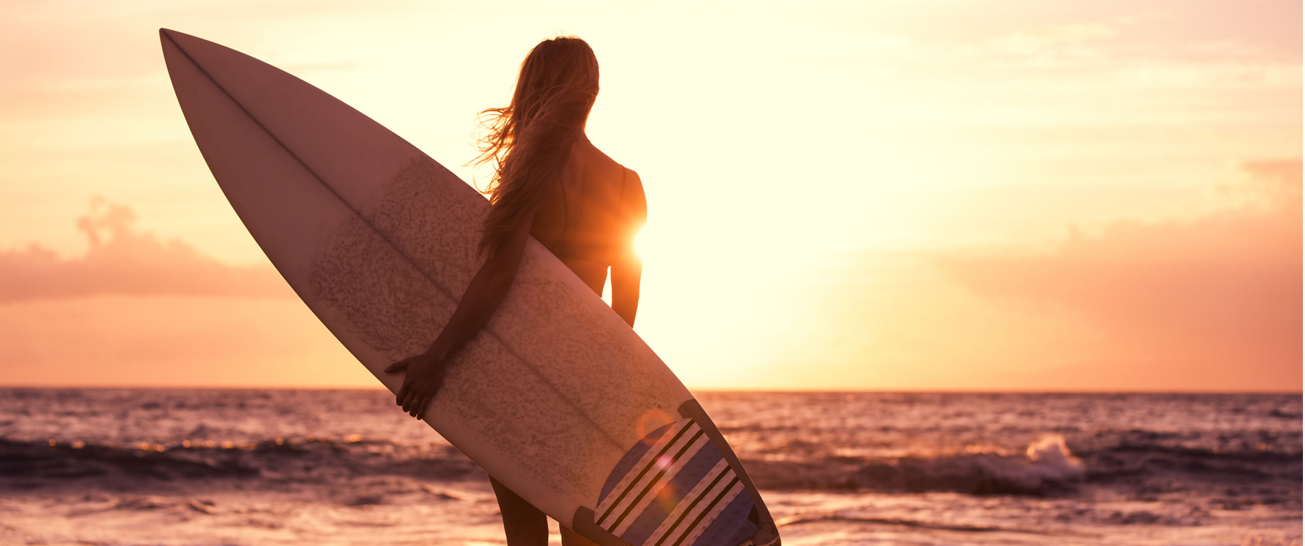 Photo of a girl on the beach holding a surf board